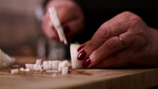 Woman's hands slicing white onion with kitchen knife closeup.