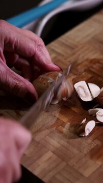 Woman's hands slicing portobello mushrooms on cutting board.