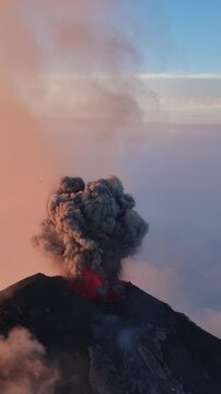 Aerial view of Volcan de Fuego erupting with a large ash plume rising into the sky during sunset in Yepocapa, Chimaltenango Department, Guatemala.