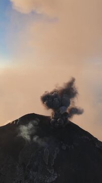 Aerial view of Volcan de Fuego erupting with thick ash plumes rising from the volcanic crater above the rugged landscape of Yepocapa, Chimaltenango Department, Guatemala.
