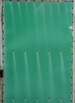 Green painted metal door with rivets and weathered texture background with copy space