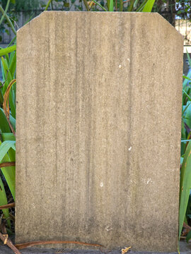 Blank weathered stone marker in garden with copy space for memorial or signage concept