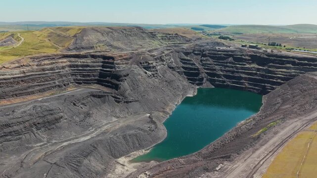 Flooded pit at abandoned Ffos-y-Fran opencast coal mine near Merthyr Tydfil, South Wales, deep water filling base of terraced excavation, aerial view