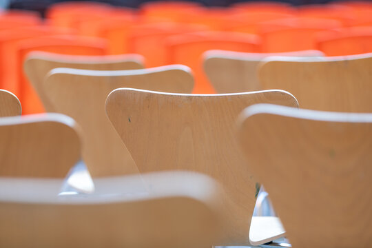 The backs of wooden chairs arranged in rows for a public event.