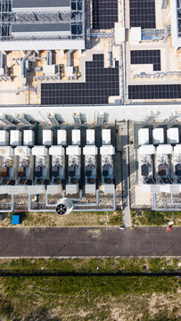 Aerial view of a hyperscale data center campus under construction featuring rows of cooling units and solar panels on the roof, situated in Melegnano, Lombardy, Italy.