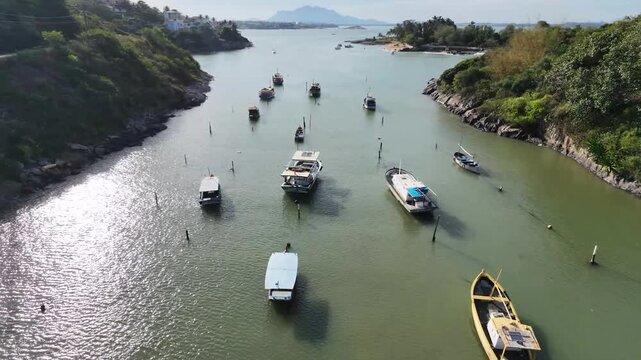 Low drone flight over traditional wooden fishing boats floating in clear coastal water between beaches