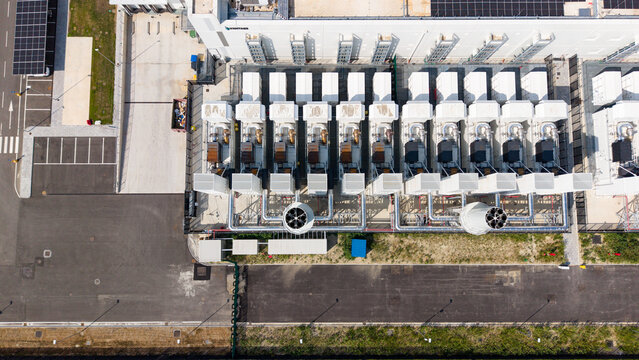 Aerial view of a hyperscale data center campus featuring industrial cooling units, infrastructure, and solar panels in Melegnano, Lombardy, Italy.
