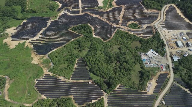 Aerial view of Sikatuna Solar Power Plant with rows of solar panels installed on hilly terrain in Sikatuna, Central Visayas, Philippines.