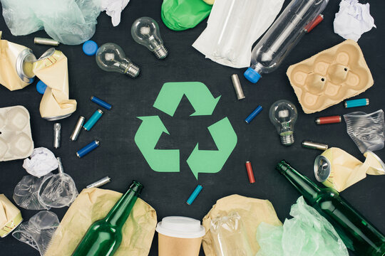 Recyclable Garbage Items Surrounding Green Recycle Symbol for Waste Management Concept Stock Photo