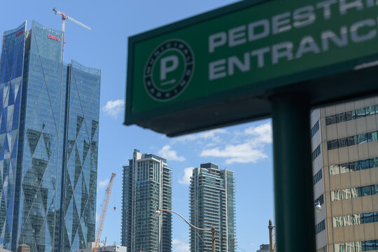 defocused Municipal Parking sign on a blue sky with view of CIBC Square and condominium complexes, Toronto