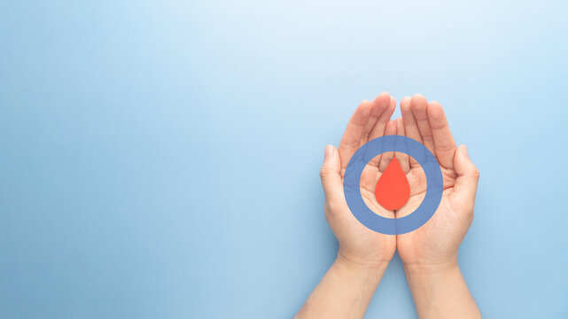 World diabetes day awareness concept. Hands holding blood drop and blue circle of universal symbol for diabetes. Support for the fight against diabetes.