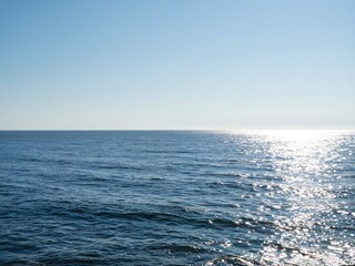 Obraz premium Calm sea surface with sunlight reflection on clear day