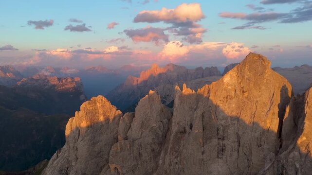 Aerial view of the jagged peaks of the Dolomites at sunset with golden light hitting the rock faces in San Martino di Castrozza, Trentino-Alto Adige, Italy.