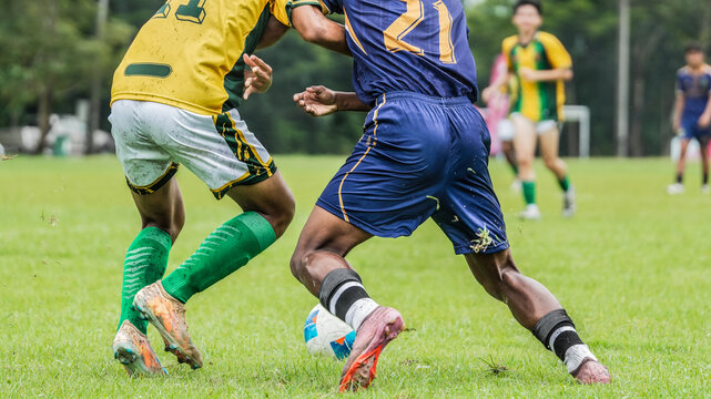 Soccer players battling for ball possession during competitive football match on outdoor grass field