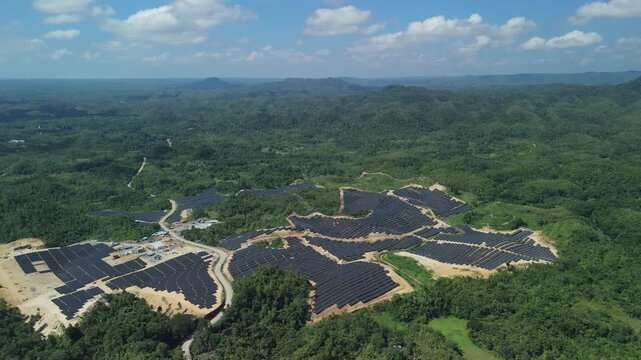 Aerial view of the Sikatuna Solar Power Plant featuring rows of solar panels nestled among lush green hills in Sikatuna, Central Visayas, Philippines.