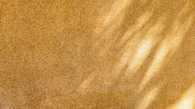 Sunlight creates patterns on a sandy surface. The scene shows a close-up view of light reflecting off the sand grains. This occurs during daylight in an outdoor environment