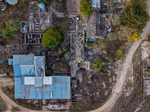 Aerial view of the industrial site near Cape River with corrugated metal roofs and dirt tracks surrounded by dry vegetation in Charters Towers Regional, Queensland, Australia.