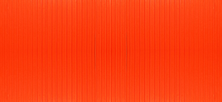 Corrugated red metal shipping container wall texture. Vertical steel panels background for industrial, logistics, and transportation design. Bright red metallic surface with grunge details.