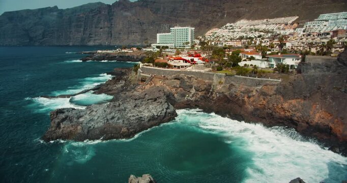TENERIFE, CANARY ISLANDS, SPAIN, 2023 April: Rescue helicopter flies over a stormy ocean near rocky coastline. Charco de Isla Cangrejo. Los Gigantes cliffs.