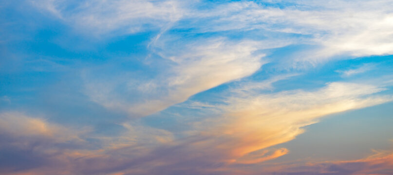 Ethereal heaven background with floating wispy clouds and colorful sunset tones on bright blue surface