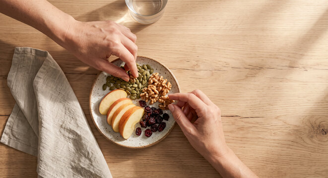 Couple Hands Reaching for Healthy Snack with Apple, Nuts and Seeds