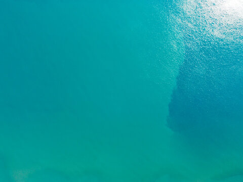 Aerial drone view of turquoise sea surface. Top down shot of crystal clear turquoise water.