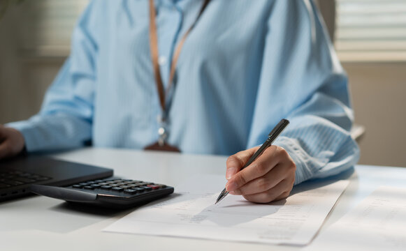 Professional accountant reviewing financial documents with calculator and laptop for budget planning, expense analysis, bookkeeping, accounting records, financial reporting and office administration.