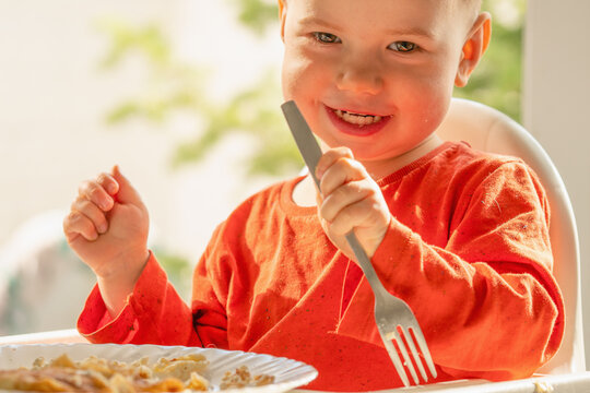 Little child discovering the joy of self-feeding with cottage cheese pancakes.