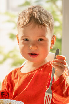 Happy toddler proudly holding a fork after enjoying homemade cottage cheese crepes.