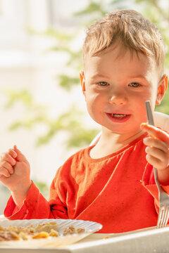 Young child happily eating traditional cottage cheese filled crepes with a fork.