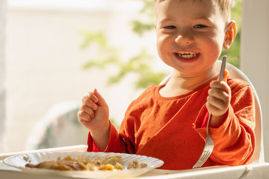 Preschool child learning independent eating while enjoying sweet cheese pancakes.