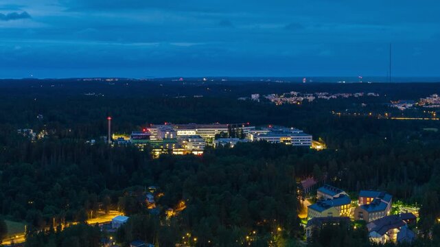 Aerial view of Jorvi Hospital and Espoo Hospital illuminated at night amidst the surrounding forest landscape in Espoo, Uusimaa, Finland.