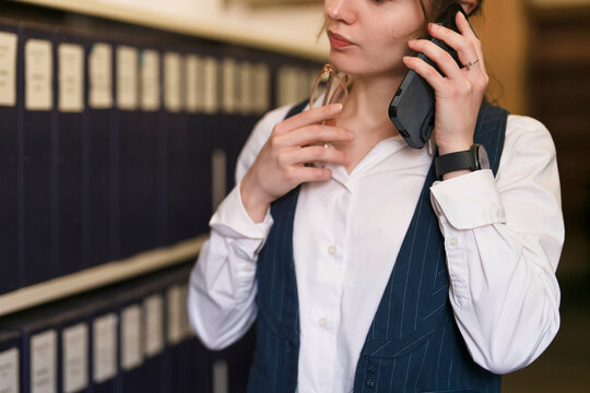 Businesswoman on phone in office with files on shelves during work hours