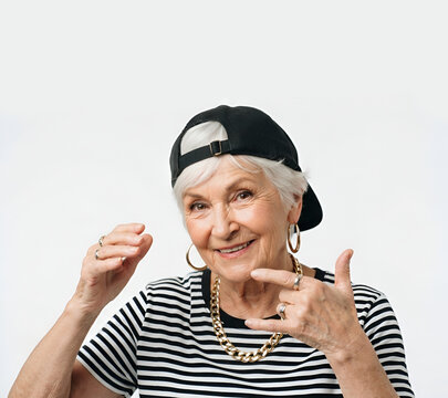 Grand-m&egrave;re d&eacute;cal&eacute;e et insolente faisant des signes de mains fa&ccedil;on gangster, look streetwear original avec marini&egrave;re et casquette