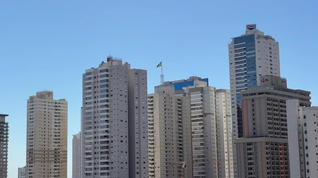 Goi&acirc;nia, Goi&aacute;s, Brasil - 27 de julho de 2026: Bandeira do Brasil em uma cobertura com vista para o horizonte urbano sob c&eacute;u azul