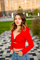 a beautiful young girl walking in the summer in a red sweater, a girl in the park in the summer, a...