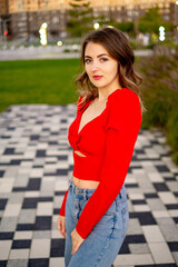 a beautiful young girl walking in the summer in a red sweater, a girl in the park in the summer, a...