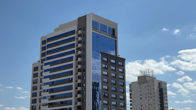 Goi&acirc;nia, Goi&aacute;s, Brasil - 28 de julho de 2026: Timelapse de dois edif&iacute;cios modernos no Setor Bueno sob c&eacute;u azul e nuvens