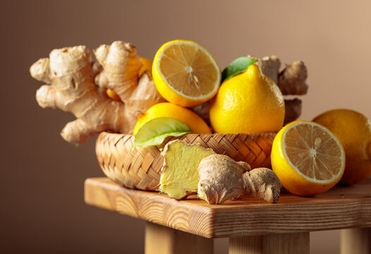 Fresh organic lemons and ginger roots on a rustic wooden board.