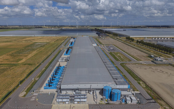 Aerial view of Google data center Agriport A7 with industrial buildings, blue cooling units, and water tanks, set among fields in Middenmeer, North Holland, Netherlands.
