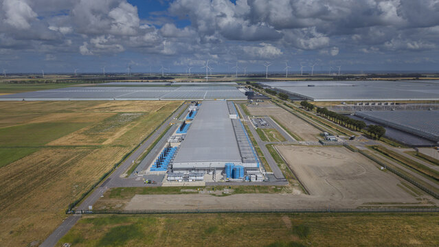Aerial view of the Google data center at Agriport A7 surrounded by vast greenhouses and wind turbines in the landscape of Middenmeer, North Holland, Netherlands.