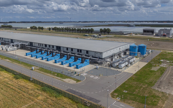 Aerial view of the Google data center at Agriport A7 featuring industrial buildings, blue cooling units, and water tanks in agricultural fields in Middenmeer, North Holland, Netherlands.