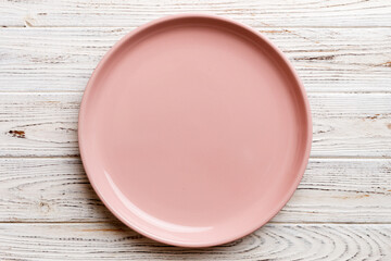 Obraz premium Top view of empty pink plate on wooden background. Empty space for your design