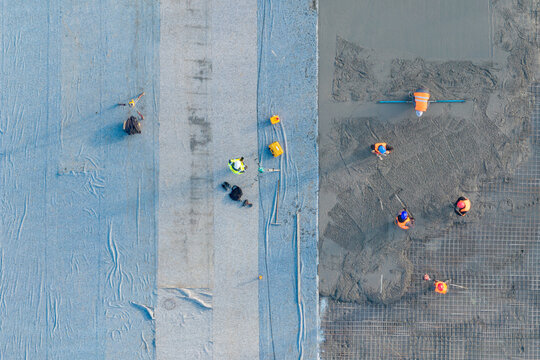 Aerial view of construction workers pouring and finishing a reinforced concrete slab at an industrial construction site in Zemun, Vojvodina, Serbia.