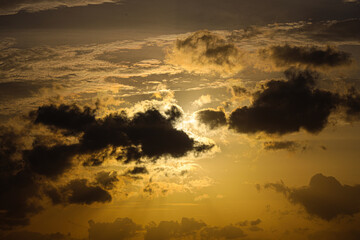 Clouds drift across the horizon while the sun illuminates the atmosphere with a warm golden light. © Sumith