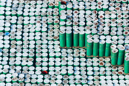 Aerial view of hundreds of green steel drums stacked in an industrial storage yard, forming a striking geometric pattern in Zemun, Vojvodina, Serbia.