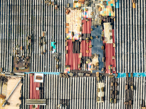 Aerial view of the roof of an informal settlement featuring corrugated metal sheets, scattered bricks, and makeshift patches in Zemun, Vojvodina, Serbia.