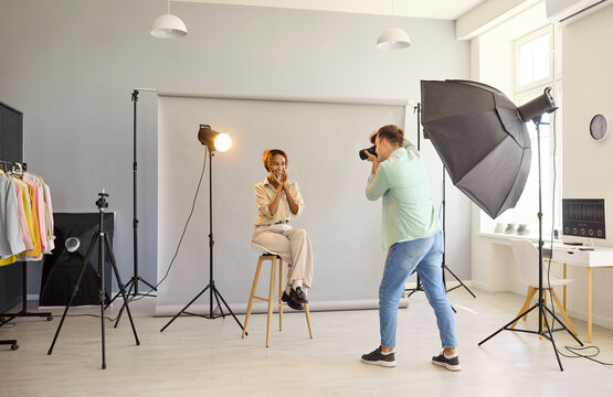 Photographer and model portrait in studio lighting. Woman smiles as photographer shoots portrait. Clean backdrop and camera support an efficient studio setup. Strong studio portrait concept now.