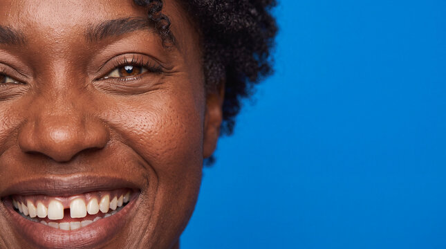 Close up of smiling Black woman with natural skin and gap teeth against blue background