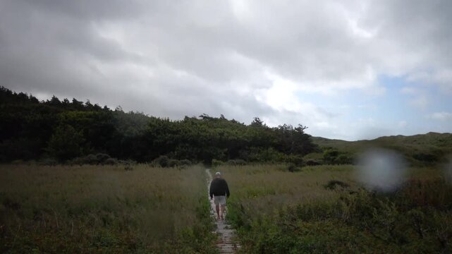 Hirtshals, Denmark A man walks on a boardwalk through the dunes on a hiking path in the rain. 